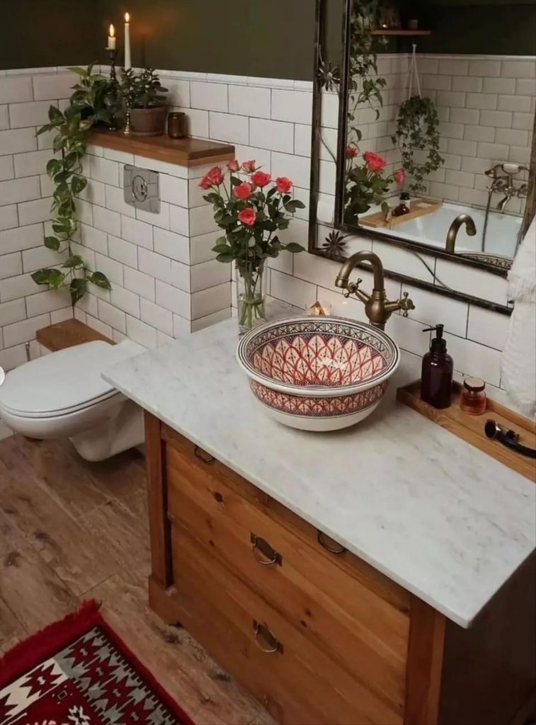 Let's talk about how to decorate the perfect boho bathroom. I noticed some common themes in the bathroom below. They feature houseplants, bamboo wood trim, and teal cabinets or tiles. Keep this in mind when looking for trends in boho bathroom design. Use natural materials and try to keep your decor as unpretentious as possible.